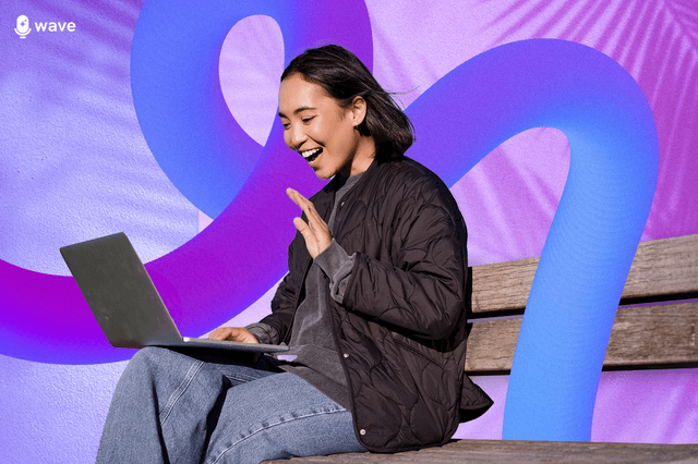A woman laughing animatedly at her laptop screen